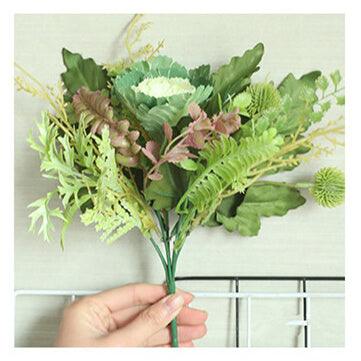 Cette image montre un bouquet de plantes vertes artificielles. Cette fausse plante est de couleur verte