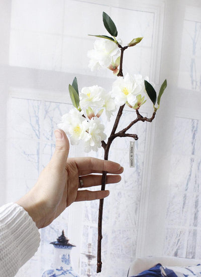 Cette image montre une fleur de cerisier artificielle. Cette fausse fleur est blanche