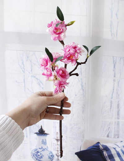 Cette image montre une fleur de cerisier artificielle. Cette fausse fleur est rose