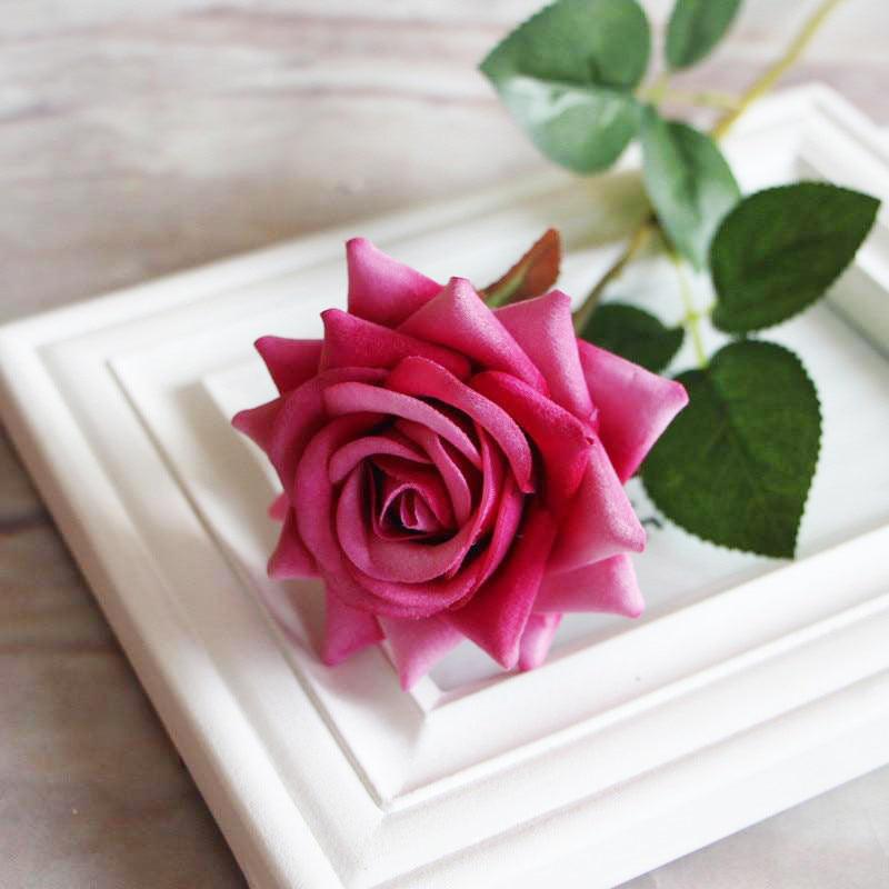 Cette image montre une rose artificielle haut de gamme en velours de couleur fuchsia 
